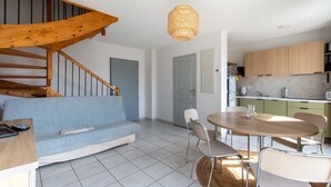 Une cuisine moderne avec des meubles en bois, une table à manger avec des chaises et un escalier doté d’une rampe en bois.