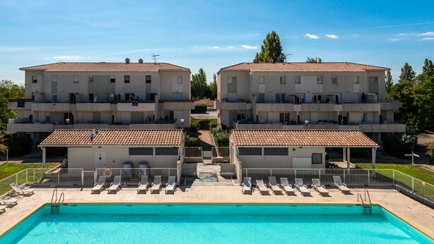 Un hôtel doté d’une piscine, de bâtiments à deux étages et offrant une vue sur un ciel dégagé.