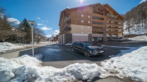 A multi-story building with a ski lift visible in the background, suggesting a ski resort setting. - Nice apt near the slopes 7 people (Allos)