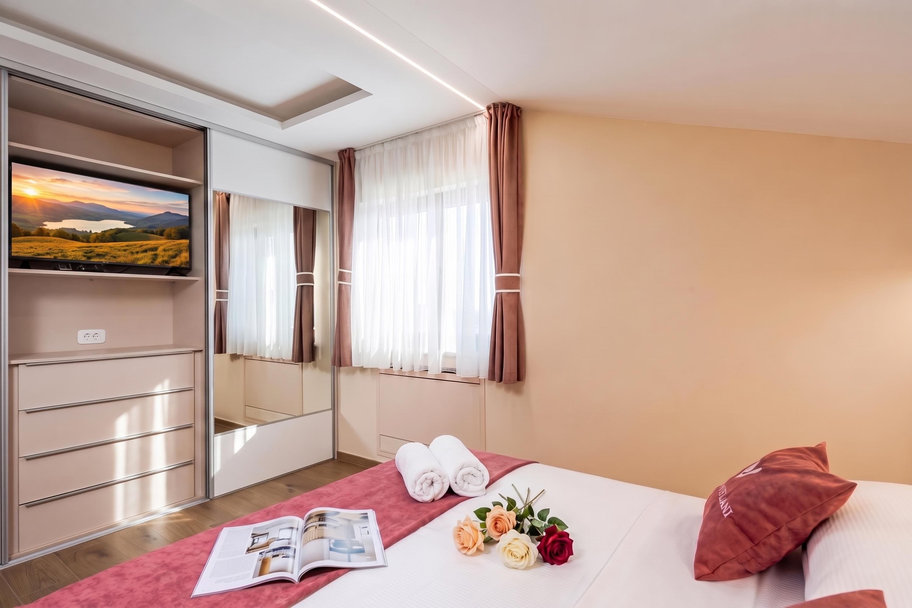Una habitación de hotel con cama, televisión, armario y ventana con cortinas.