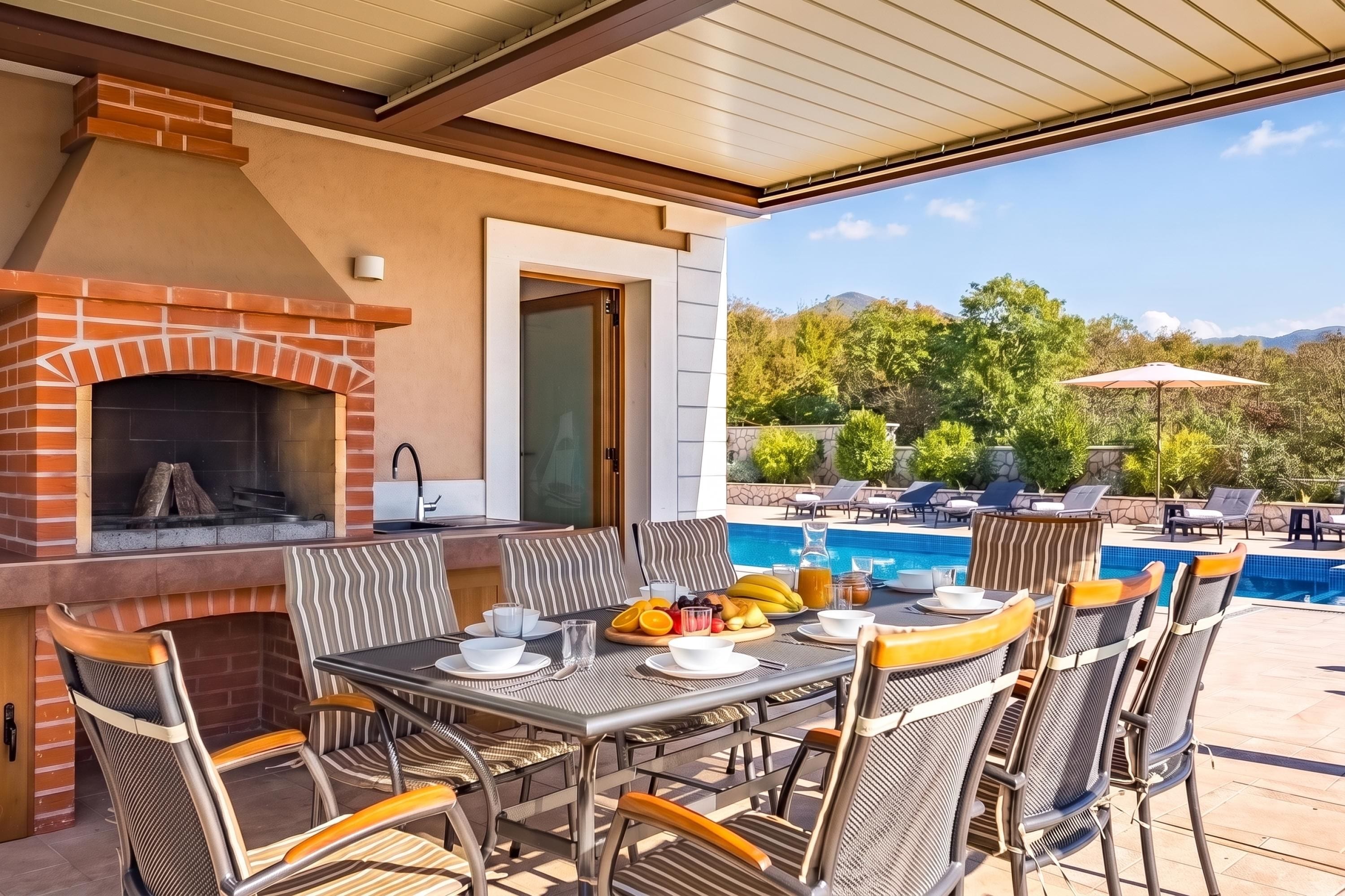 An outdoor dining area with a brick fireplace, a pool, and lounge chairs.