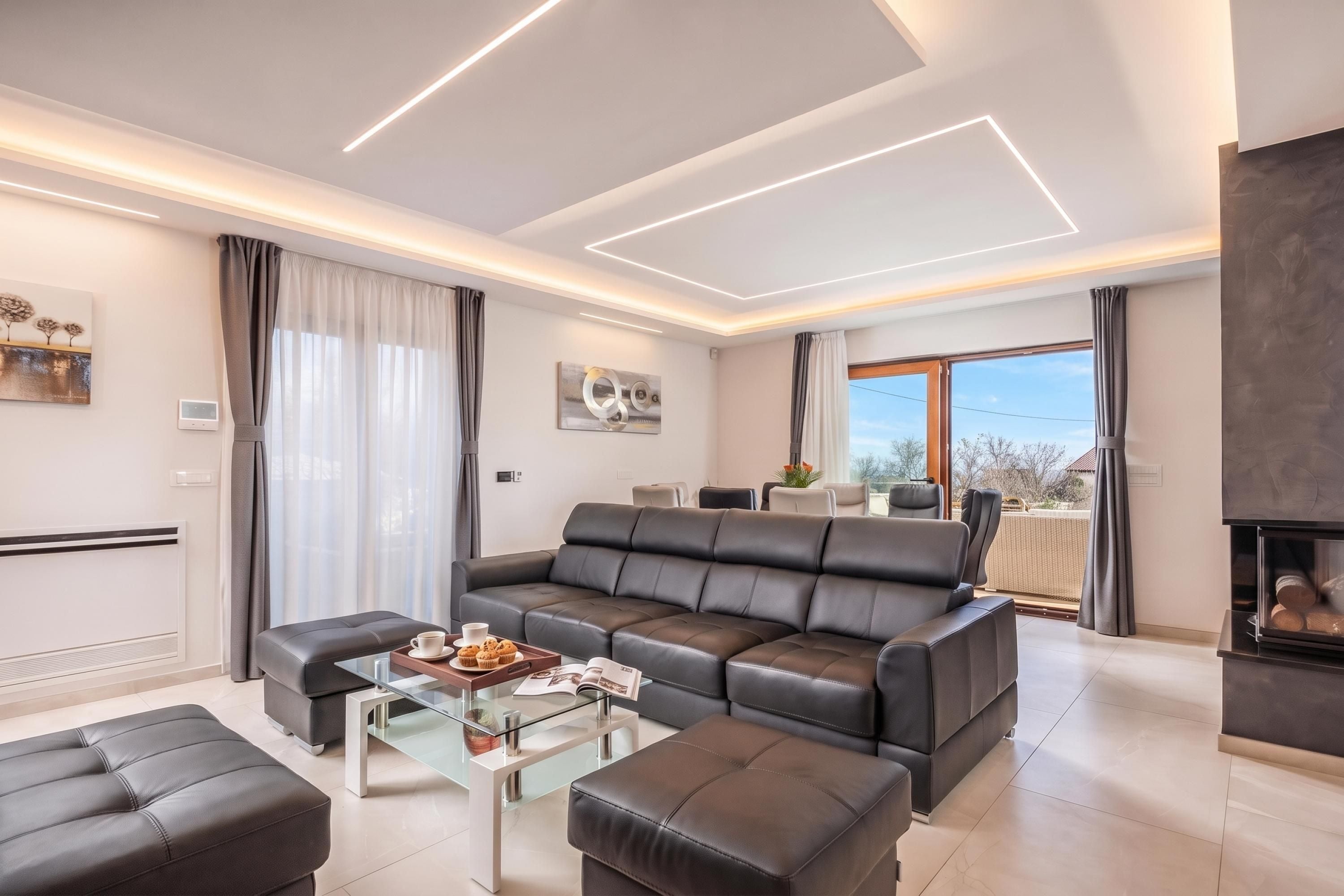 A modern living room with a sectional sofa, a glass coffee table, and a fireplace.