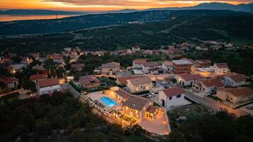 A residential area with houses, a swimming pool, and a hilly landscape in the background.