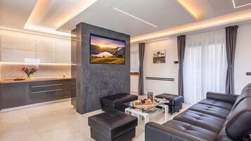 A modern living room with a sofa, ottomans, a coffee table, and a painting on the wall.