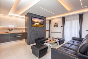 A modern living room with a sofa, ottomans, a coffee table, and a painting on the wall.