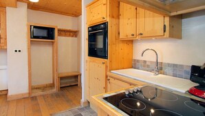 A kitchen with wooden cabinets, a microwave, an oven, a sink, and a stove. - Apt 4/6 ppl, terrace with a very nice view (Les Deux Alpes)