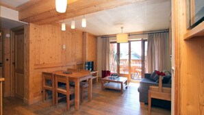 A wooden interior with a dining table, chairs, a sofa, and a TV. - Apt 4/6 ppl, terrace with a very nice view (Les Deux Alpes)