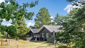 Een houten chalet met twee verdiepingen, een schuin dak, een veranda en een klein terras.