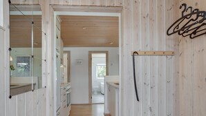 Een smalle gang met houten wanden en een houten vloer die naar een badkamer leidt.