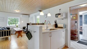 Een moderne keuken met een centraal eiland, houten plafond en een eethoek met een tafel en stoelen.
