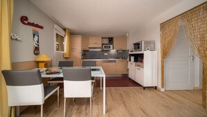 A compact kitchen with a dining area, featuring a microwave, oven, and cabinets.