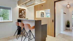 Eine moderne Bar mit Holzvertäfelung, einer Bar und drei Barhocker.
