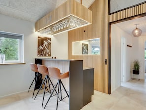 Un espace bar moderne avec un lambris en bois, un comptoir et trois tabourets de bar.