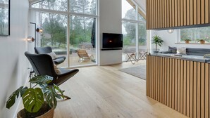 Ein modernes Wohnzimmer mit einem großen Glasfenster, das in einen Außenbereich führt, einem an der Wand montierten Flachbildfernseher und einer Wand mit Holzpaneelen.