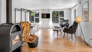 A modern living room with a wood-burning stove, a TV mounted on the wall, and a cozy seating area with chairs and a table. - "Allen" - 1km from the sea by Interhome (Blåvand)