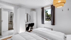 A modern bedroom with a large bed, a walk-in closet, a bathroom with a shower, and a window with curtains. - "Allen" - 1km from the sea by Interhome (Blåvand)