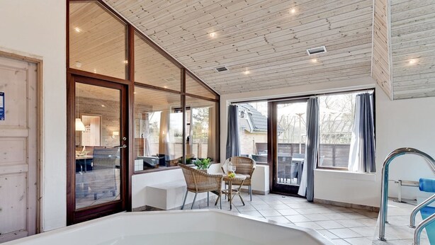 Ein modernes Badezimmer mit einer großen Badewanne, einer Duschkabine aus Glas und Blick auf die Terrassenanlage.