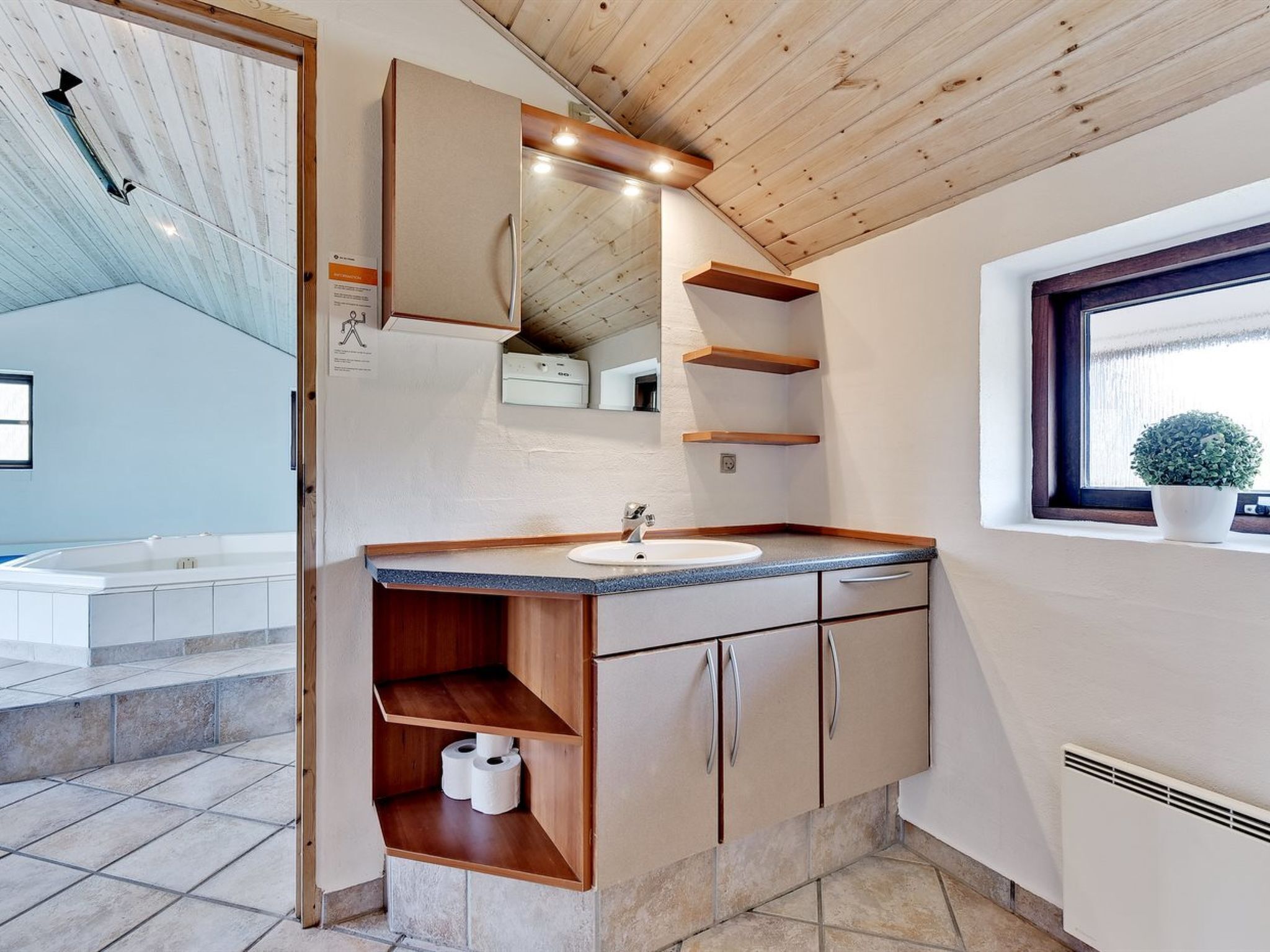 Une salle de bain moderne avec un meuble-lavabo en bois, un grand miroir et des étagères intégrées.