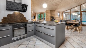 Eine moderne Küche mit einer großen Kochinsel, integrierten Geräten und einer Holzbeschichtung an der Decke.