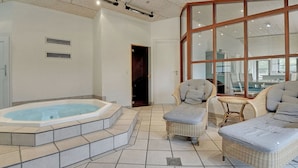 A spacious indoor area with a hot tub, wicker lounge chairs, and a large window. - "Holmved" - 1.2km from the sea by Interhome (Blåvand)