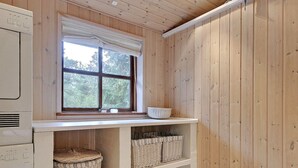 A laundry room with wooden walls, a window with a white valance, and wicker baskets on shelves. - "Holmved" - 1.2km from the sea by Interhome (Blåvand)