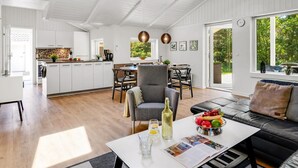 A spacious living area with a dining table, a sofa, and a kitchen area with white cabinets.