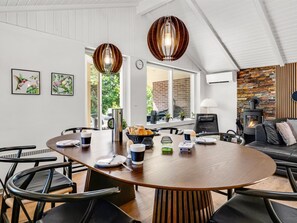 Una sala de estar moderna con una mesa de comedor de madera, sofás de cuero negro y una chimenea de piedra.