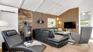 A modern living room with a stone wall, a fireplace, a sofa, a TV, and a wooden panel wall.
