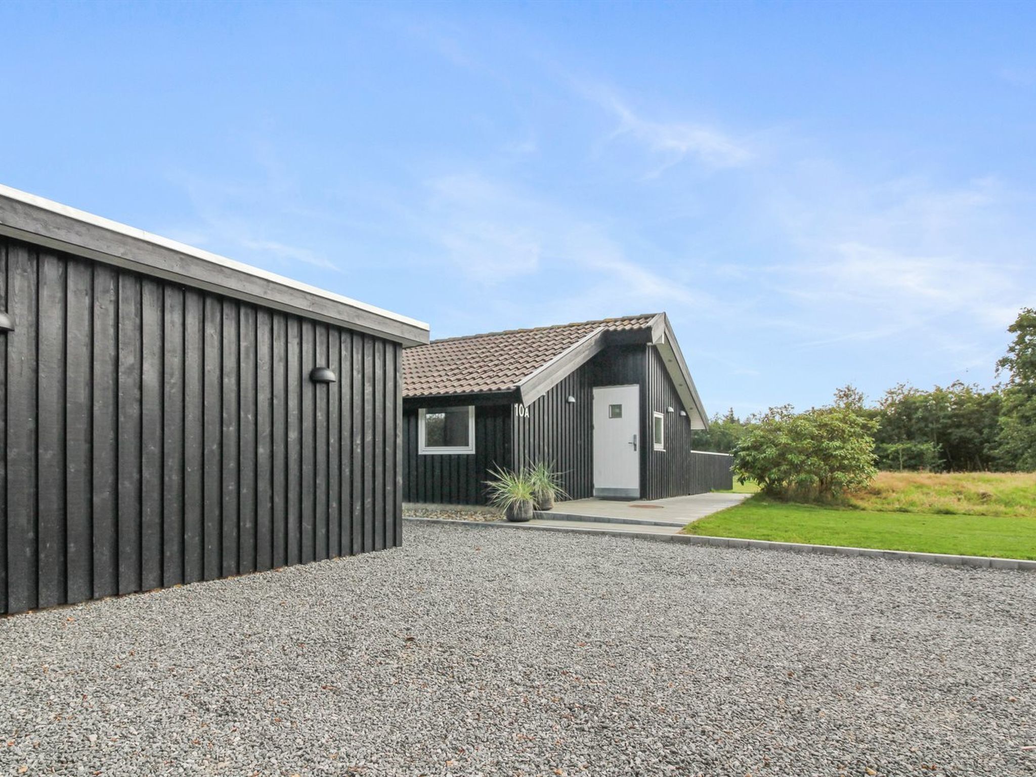 Un bâtiment moderne avec une allée gravillonnée et un petit jardin.