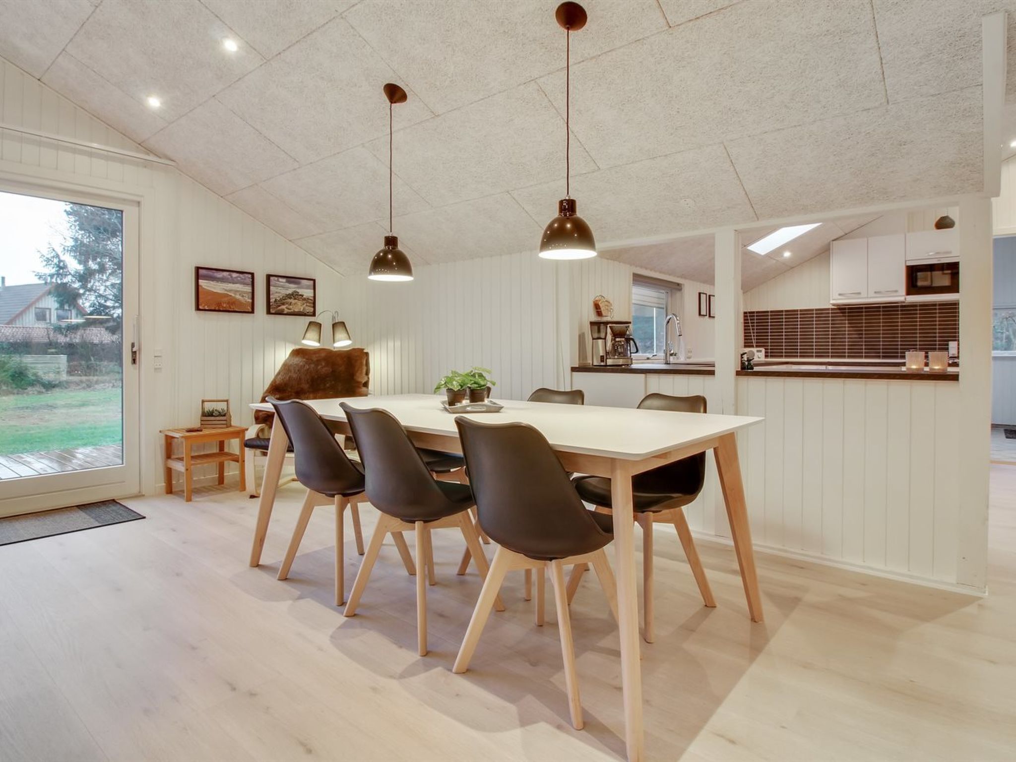 A modern kitchen with white cabinets, a wooden countertop, and a hanging light fixture.