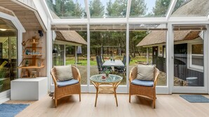 A spacious room with large glass windows, wicker furniture, and a view of an outdoor area with a table and chairs. - "Verna" - 800m from the sea by Interhome (Blåvand)