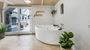 A modern bathroom with a freestanding bathtub, a glass door leading to a balcony, and a potted plant. - "Verna" - 800m from the sea by Interhome (Blåvand)