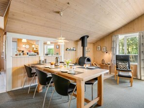 Een gezellig interieur van een chalet met een eethoek, keuken en een open haard.