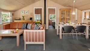 A cozy cabin interior with a wooden ceiling, a dining area with chairs and a table, a sofa with cushions, and a kitchen area with cabinets. - "Valpuri" - 1.3km to the fjord by Interhome (Blåvand)