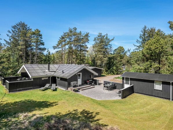 Eine Lodge mit einer großen Terrasse, Sitzgelegenheiten im Freien und einem überdachten Bereich.