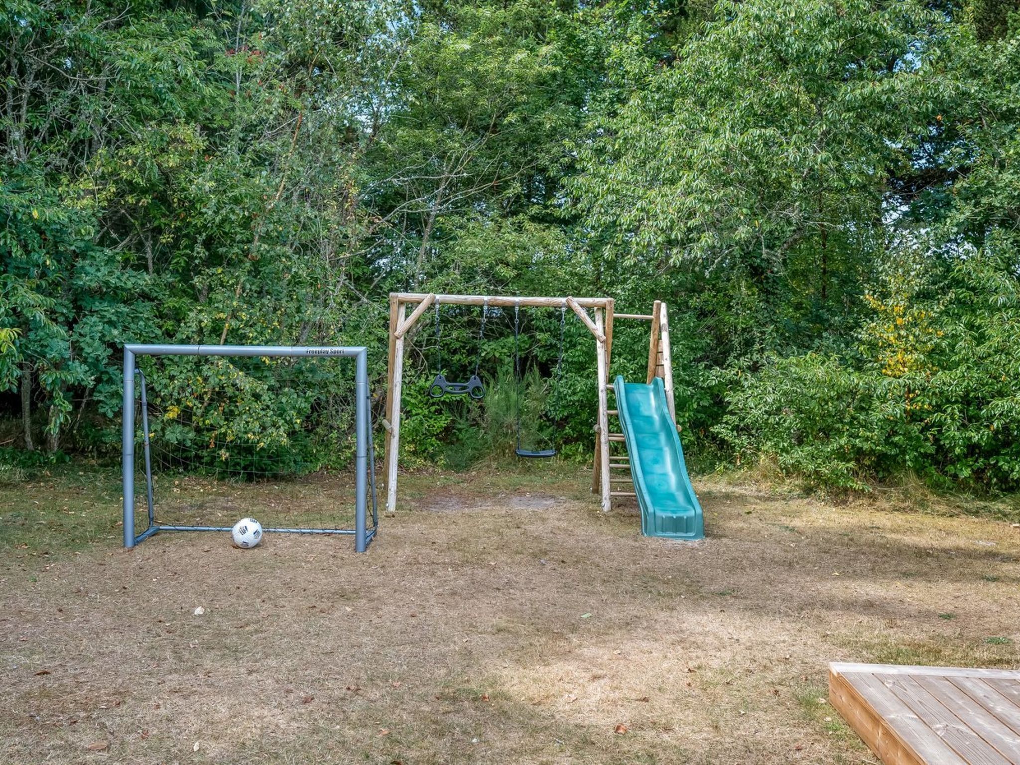 A playground with a soccer goal, a swing set, and a slide.