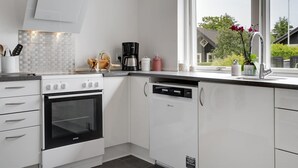 A modern kitchen with white cabinets, a black oven, and a coffee maker. - "Jörgen" - 100m from the sea by Interhome (Esbjerg V)