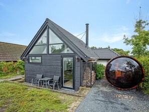 Een modern huis met een schuin dak, grote ramen en een klein terras met zitplaatsen.