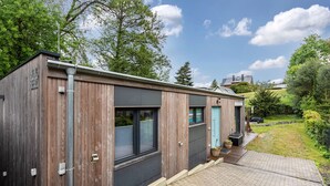 Een modern houten gebouw met grote ramen, een garage en een verharde oprit.