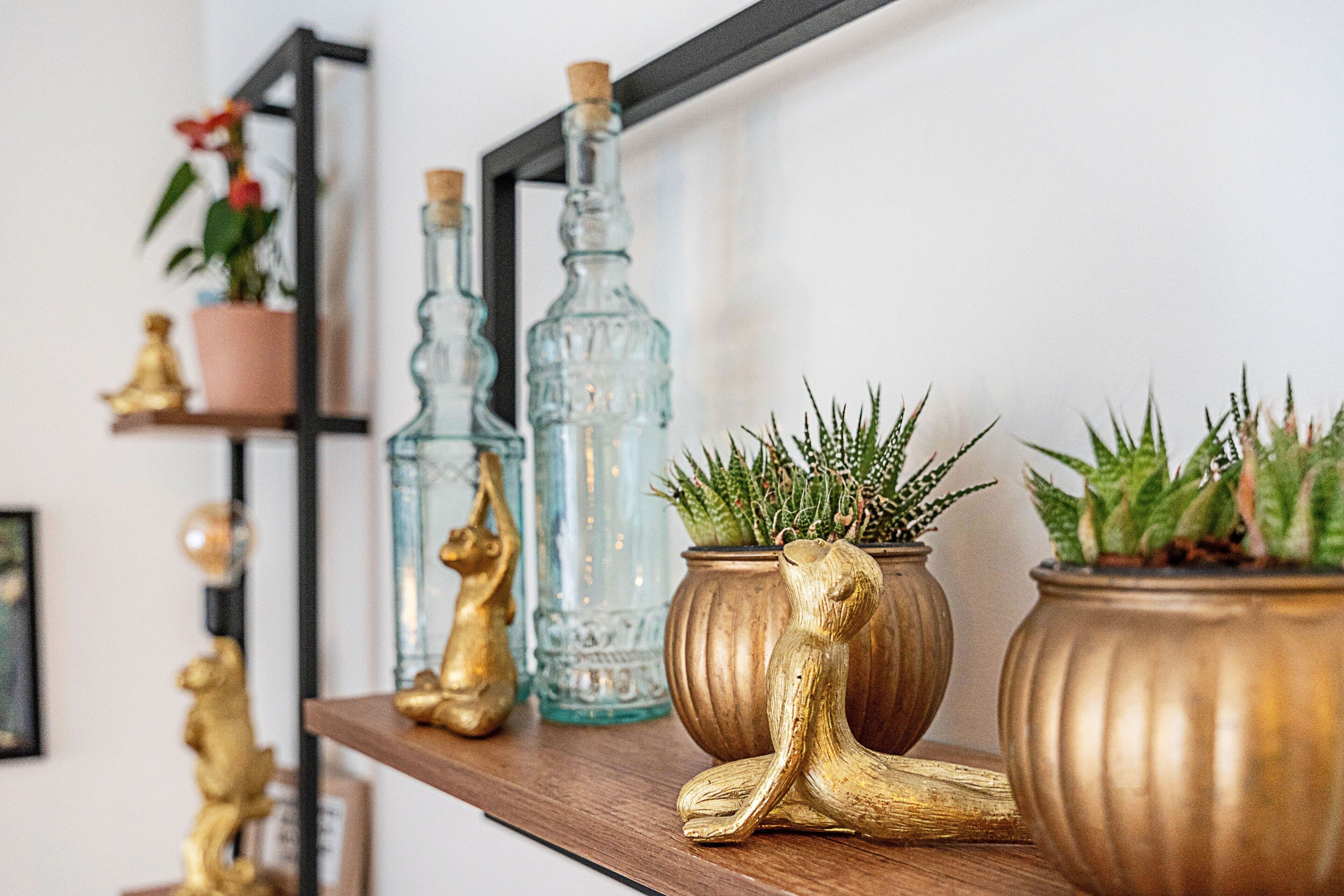 A shelf with decorative items including glass bottles, golden figurines, and potted plants.