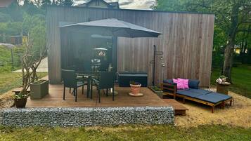 Un patio con mesa y sillas, un sofá, un pequeño jardín y una valla de madera.