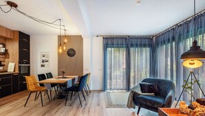Een moderne woonkamer met een eetgedeelte, een bank en een groot raam met gordijnen.