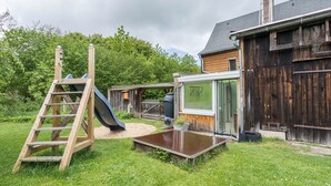 Una casa de madera con un tobogán, una escalera y una pequeña terraza.