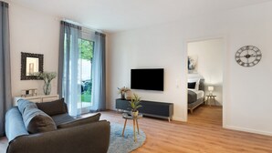 Ein modernes Wohnzimmer mit einer Couch, einem Fernseher und einem Essbereich mit Tisch und Stühlen.