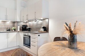 A modern kitchen with white cabinets, a built-in oven, and a coffee maker on the counter.