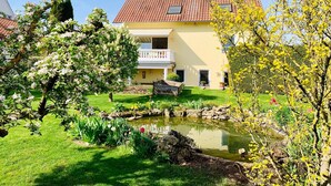 A two-story house with a balcony, a pond, and a garden. - Apartment 'Ferienwohnung Mit Terrasse, Garten' with Private Terrace, Private Garden and Wi-Fi (Gotha)