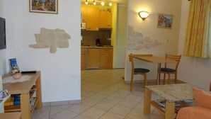 A living room with a dining area, a kitchen in the background, and a stone wall decoration. - Apartment 'Ferienwohnung Mit Terrasse, Garten' with Private Terrace, Private Garden and Wi-Fi (Gotha)