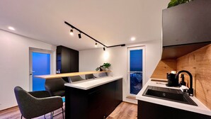 A modern kitchen with a central island, bar stools, a built-in oven, and a window with a view.