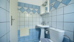 A bathroom with blue and white tiles, a white sink, a toilet, and a shower area. - Milos Studios & Beach House (Sfakia)