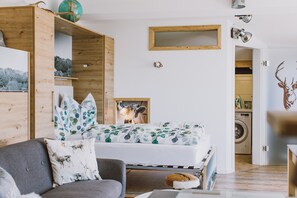 Quarto com uma cama, um sofá cinza, um guarda-roupa de madeira, um globo e um espelho na parede.